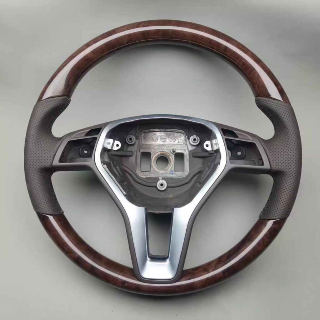 2013 mercedes cls 550(walnut wood trim at the 12 and 6 o'clock positions, an airbag cover with a black Mercedes logo,orange stitch on airbag perforated leather grips, and control buttons; black stitching)